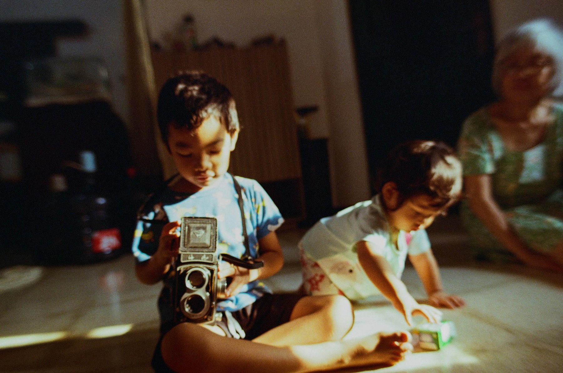 Rio memegang kamera TLR Seagull, Kirana memegang bungkus film