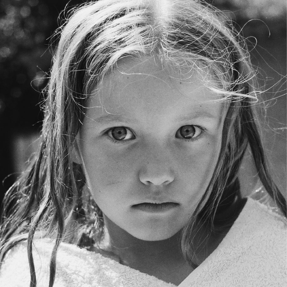 Close portrait of a young girl looking into the camera, from REINKARNASI