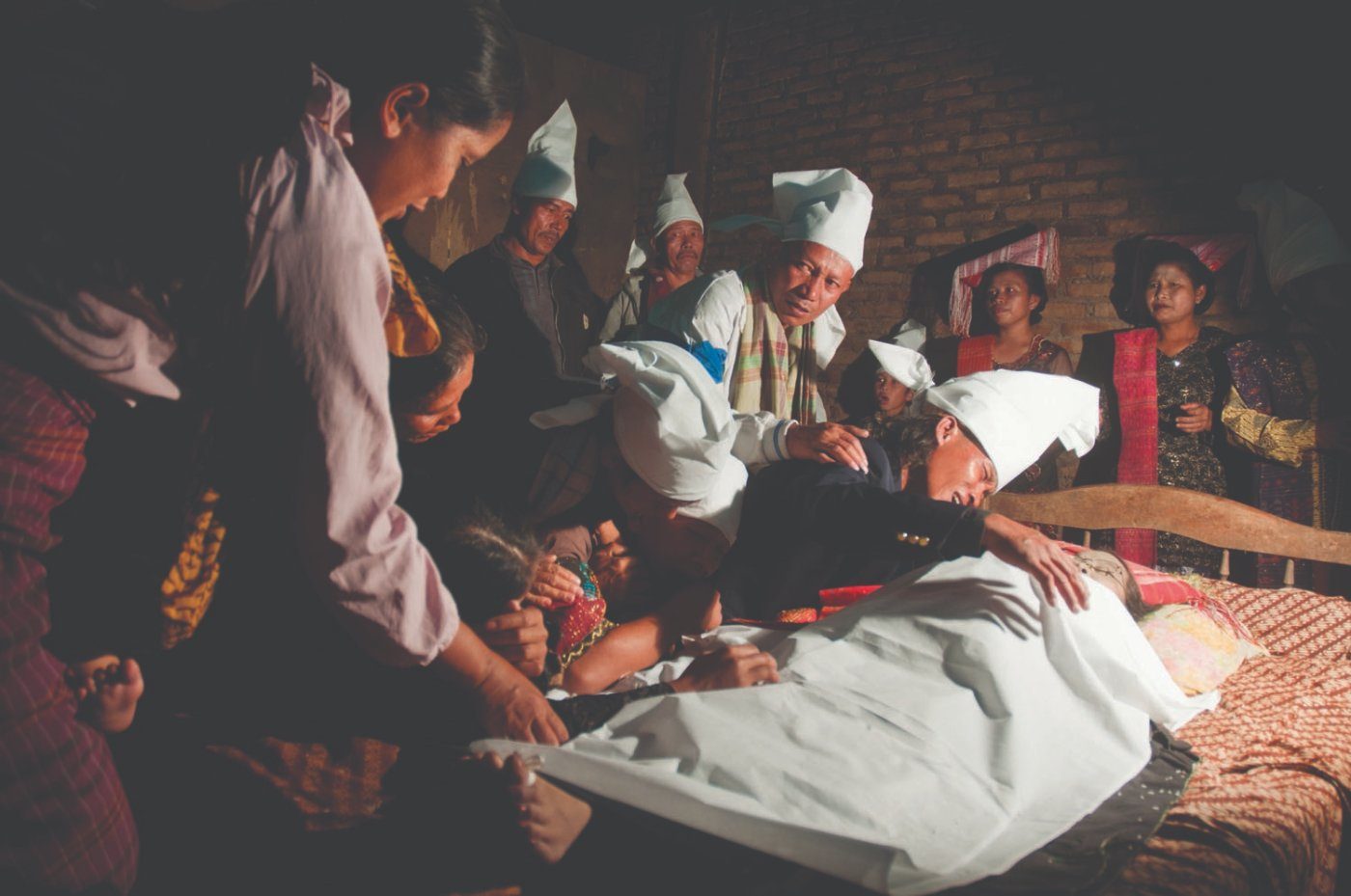Mourners gathered around a body wrapped in cloth at a Batak funeral, Simalungun