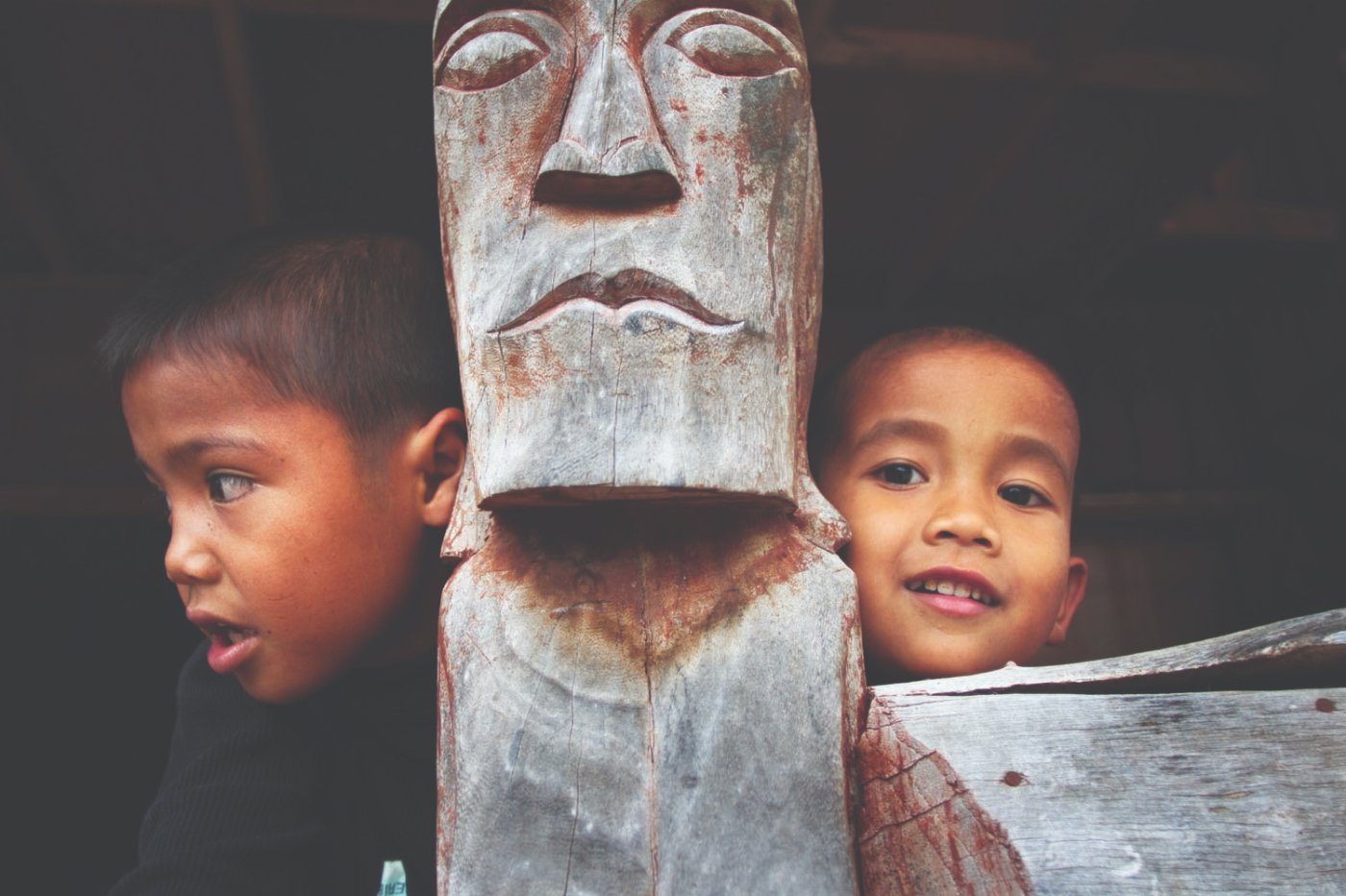 Two boys beside a carved wooden figure at Huta Sialagan, Samosir