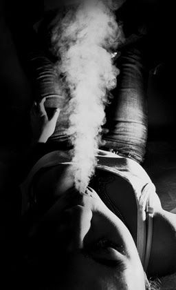 Smoke rising from a man lying on his back, seen from above his head