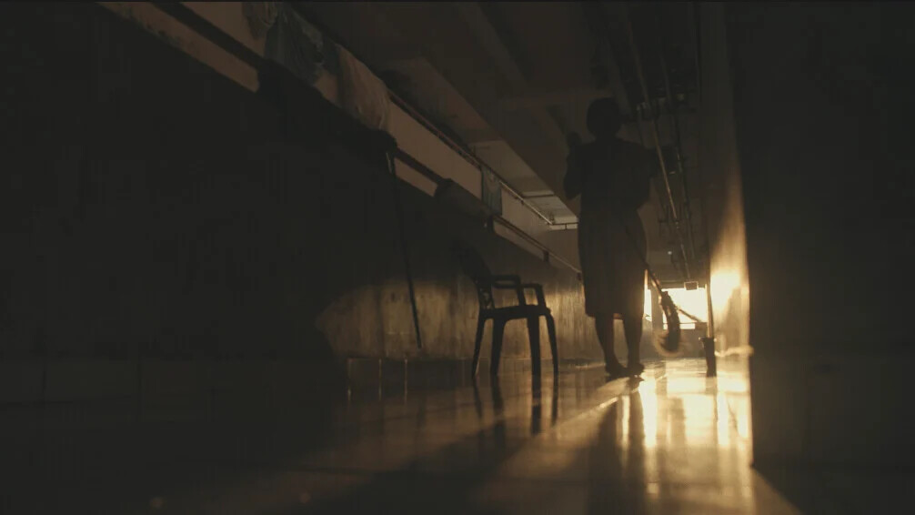 A silhouetted figure walking down a dim, backlit corridor, from Terpejam untuk Melihat